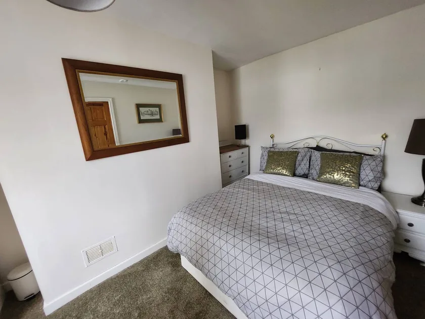 Double bed with patterned bedding, matching bedside furniture and a framed wall mirror.